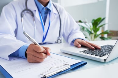 maos-da-medica-irreconhecivel-escrevendo-no-formulario-e-digitando-no-teclado-do-laptop-2-scaled